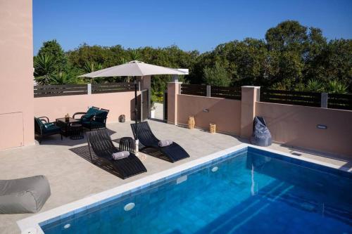 a swimming pool with chairs and an umbrella at Jasmine Loft Luxury 2 in Kokkíni Khánion