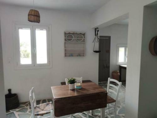 ein Esszimmer mit einem Holztisch und weißen Stühlen in der Unterkunft Anna's Cottage Home in Galini