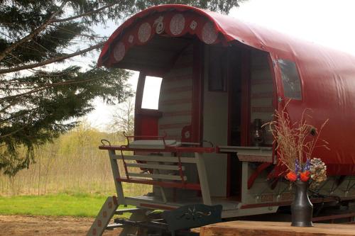 einem roten Zugwagen mit einer Veranda auf einem Tisch in der Unterkunft Roulotte irlandaise Polly in Saint-Vincent-en-Bresse