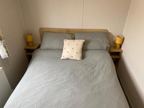 a bed with two blue pillows and two yellow candles at Cosy holiday home at Romney Sands in New Romney