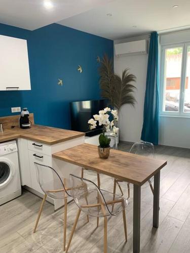 une cuisine avec une table et des chaises et un mur bleu dans l'établissement Appartement Etat neuf La Chantalane -proche centre-ville, à Cannes