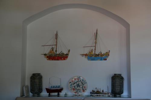 two ships hanging on a wall above a shelf at The fig tree house in Samothráki