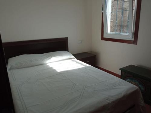 a white bed in a bedroom with a window at una terraza al atlántico in Nigrán