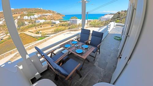 a balcony with a table and chairs and the ocean at 1Path Pelican Mykonos Super Paradise Beach House in Mýkonos City