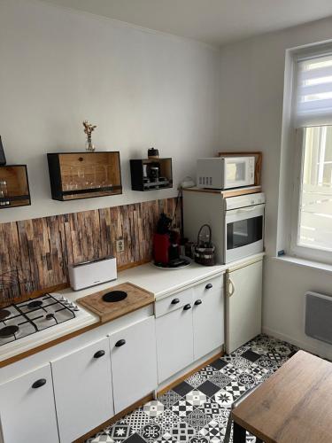 La cuisine est équipée de placards blancs, d'une cuisinière et d'un four micro-ondes. dans l'établissement Grand’Heurt 50m de la plage, à Le Portel