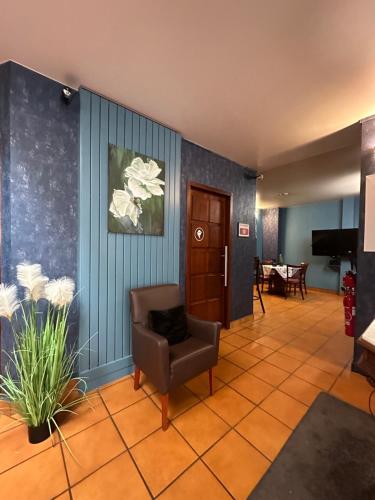 een wachtkamer met een stoel en een televisie bij L'EMBLEME - BOUTIQUE HOTEL in Beaurepaire