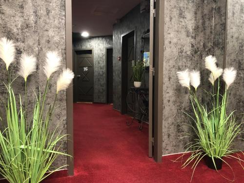 a hallway with potted plants and a red carpet at L'EMBLEME - BOUTIQUE HOTEL in Beaurepaire