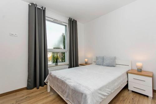 um quarto branco com uma cama e uma janela em Apartament Baltic Sea 3 - Gdańsk Przymorze em Gdansk