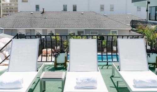 a row of white chairs on a balcony with a pool at The Shore House in Wildwood