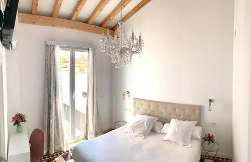 um quarto com uma cama branca e um lustre em Casa del Azucar em Motril
