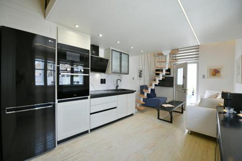a kitchen with white cabinets and a living room at Pearl House in Hydra