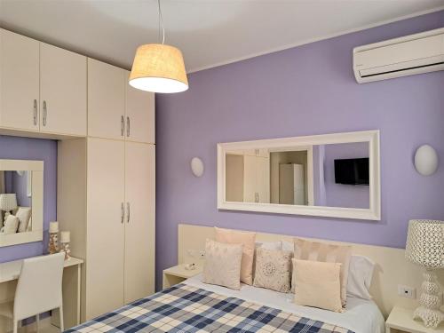 a bedroom with purple walls and a bed with pillows at Appartamento Castel Sant'Angelo in Licata