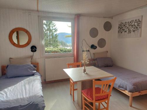 a bedroom with two beds and a table and a window at HAUT JURA 