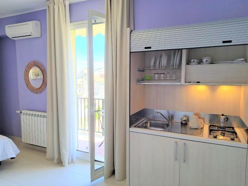 a kitchen with purple walls and a sink and a window at Appartamento Castel Sant'Angelo in Licata