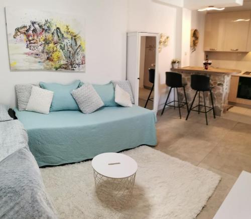a living room with a blue couch and a kitchen at Near beach studio in Kaštela