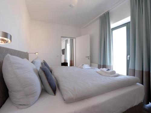 a white bedroom with a large white bed with pillows at Ohlerich Speicher App. 19 - Meerblick in Wismar