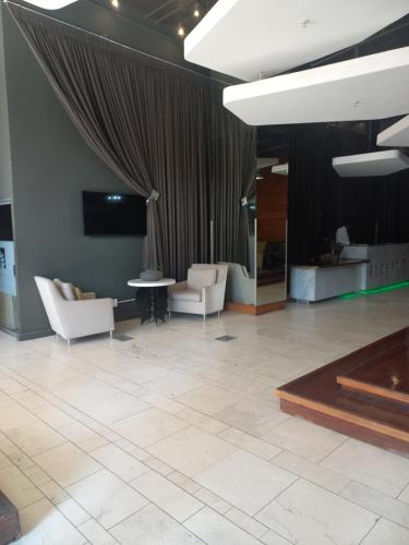 a lobby with white chairs and a television and a table at The Franklin Loft Apartments Unit 1209 in Johannesburg