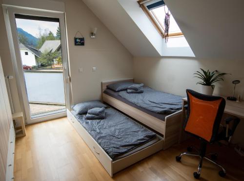 2 camas en una habitación con ventana y silla en Guest house TOMAN en Bled