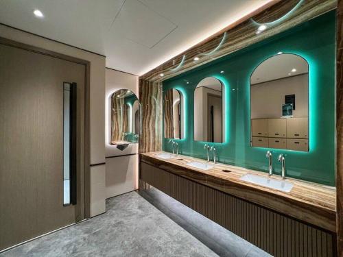 La salle de bains est pourvue de 3 lavabos et d'un mur vert. dans l'établissement The Rixx Iconic Apartment @ D1/pool/gym/Netflix, à Hô-Chi-Minh-Ville