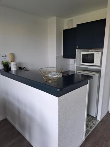 une cuisine avec un comptoir noir et un four micro-ondes dans l'établissement Résidence cap ocean port du Crouesty avec piscine, à Arzon