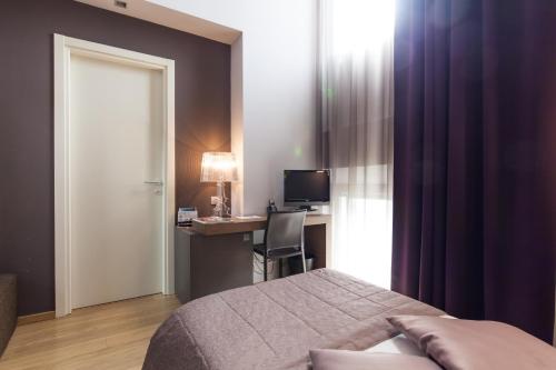 a bedroom with a bed and a desk with a computer at Hotel Michelangelo in Forlì