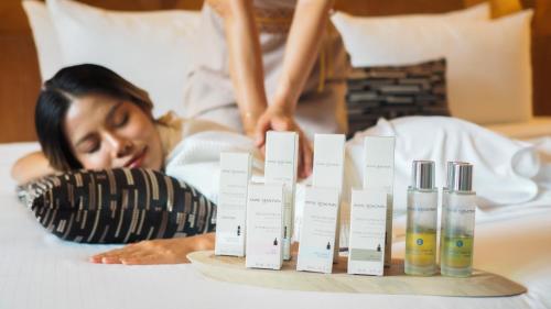 a woman laying on a bed with a set of products at La Miniera Pool Villas Pattaya - Small Luxury Hotels of the World in Nong Prue