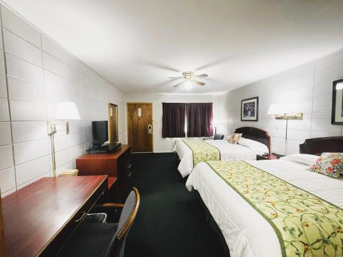 een hotelkamer met 2 bedden en een bureau bij The Madison Inn Motel in Fort Madison
