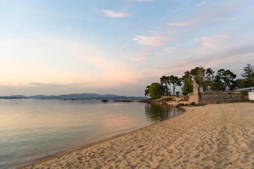 uma praia em frente a um corpo de água em Hotel Leal - La Sirena em Vilanova de Arousa