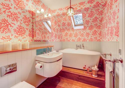 a bathroom with a tub and a toilet and a sink at Dulcima Cottage in Corfe Mullen