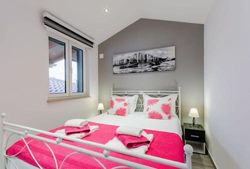 um quarto com uma cama branca com toques cor-de-rosa em Apartman Mauro em Bol