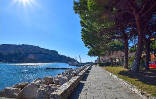 a sidewalk next to a body of water with trees at 2 Bedroom Lovely Apartment In Le Grazie in Le Grazie