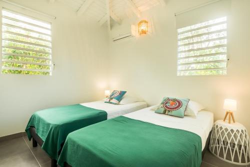 two beds in a room with white walls and windows at Villa Kokomo - St. Francis, completely renovated in Saint-François