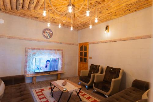 ein Wohnzimmer mit einem Sofa, Stühlen und einem TV in der Unterkunft Harmony Houses Cappadocia in Ürgüp