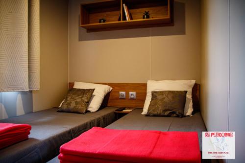 Cette chambre comprend 2 lits et une couverture rouge. dans l'établissement Mobil Home-Sa Palomera- Camping Mar Estang-Canet en Roussillon 66140, à Canet