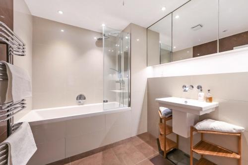 a bathroom with a tub and a sink and a shower at Stylish Apartment with BBQ Kensington in London