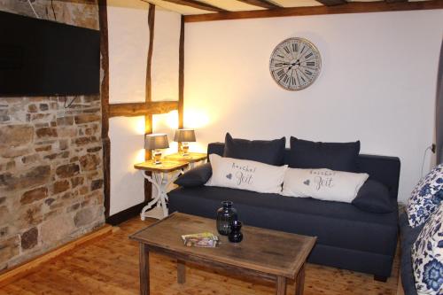 ein Wohnzimmer mit einem blauen Sofa und einer Uhr an der Wand in der Unterkunft Ferienhaus Eifelstuben mit Charme - Bauernstube Vulkaneifel - Nähe See und Burgruine in Ulmen