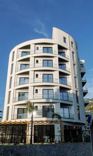 a tall white building with a palm tree in front of it at Valza Boutique Hotel in Vlorë