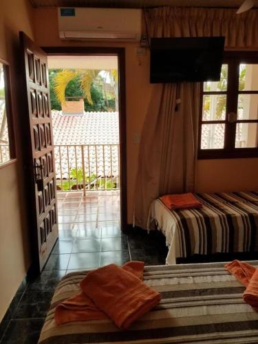 a bedroom with two beds and a television and a balcony at Hotel AATRAC Iguazú in Puerto Iguazú