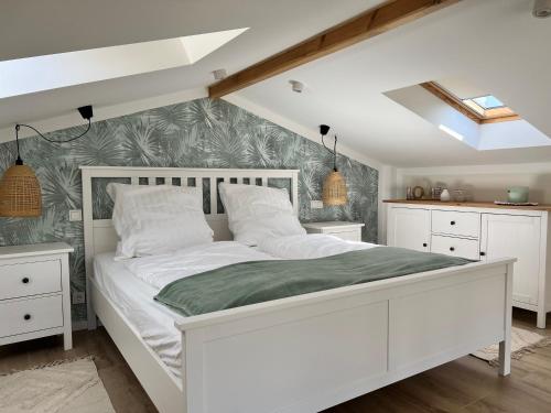 a bedroom with a white bed with a green blanket at Casa Kashubia - Nowoczesny dom wakacyjny nad jeziorem - Cisza natura i komfort in Brzeźno Szlacheckie