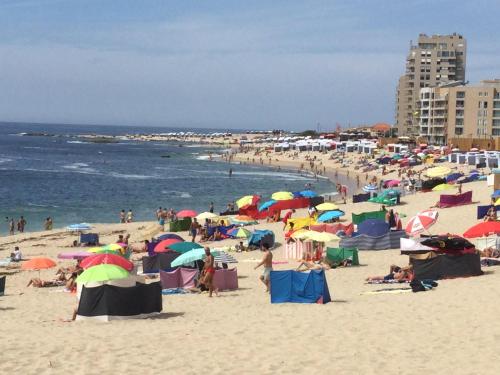 a group of people on a beach with umbrellas at Estrela de Aver o Mar in Póvoa de Varzim