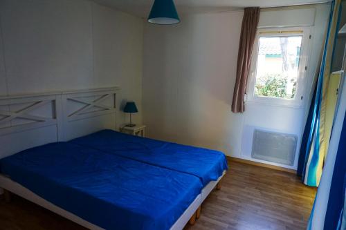 - une chambre avec un lit bleu et une fenêtre dans l'établissement Villas du lac, à Soustons