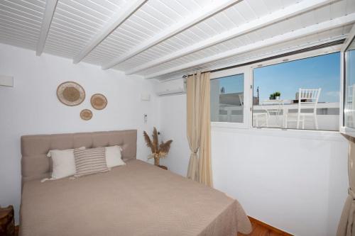 Casa Piccolino في مدينة ميكونوس: غرفة نوم بسرير ونافذة كبيرة