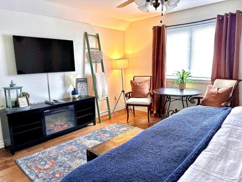 a bedroom with a bed and a flat screen tv at Settlers Suites in Niagara on the Lake
