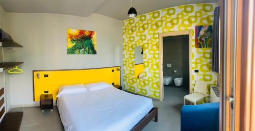 a bedroom with a white bed and a yellow headboard at Vela di Soleville camere con e senza vista lago con ristorante & pizzeria in Sale Marasino