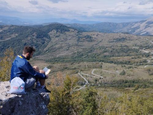 a man sitting on top of a rock reading a book at TibetiAmo in Castelsaraceno