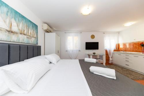 duże białe łóżko w pokoju z telewizorem w obiekcie Apartmani Valentina w mieście Zadar