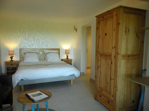 1 dormitorio con 1 cama y armario de madera en Maison Les Fraysses, en Bellefont-La Rauze