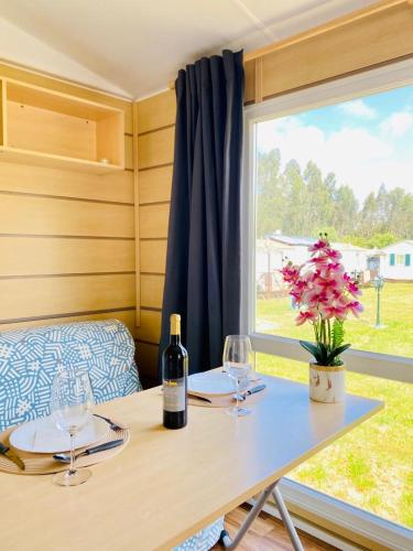 a table with two glasses and a bottle of wine at Bungalow 4x3 in Burinhosa