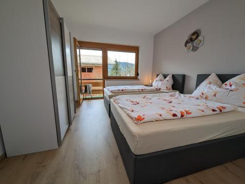 a bedroom with two beds and a window at Angerpartments-Sonnige große Wohnung mit Balkon und kostenlosen Parkplatz in Döbriach