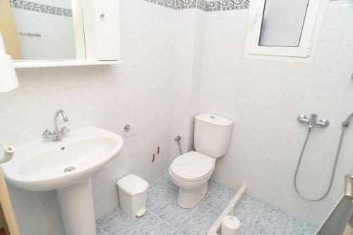 a white bathroom with a sink and a toilet at Joanna Apartments in Mikri Vigla